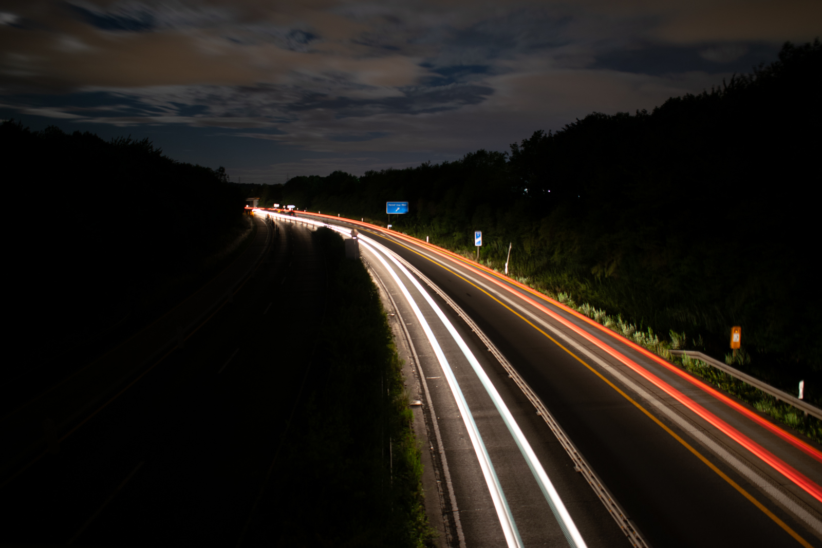 Die Scheinwerfer der Fahrzeuge auf der Autobahn werden zu leuchtenden Linien